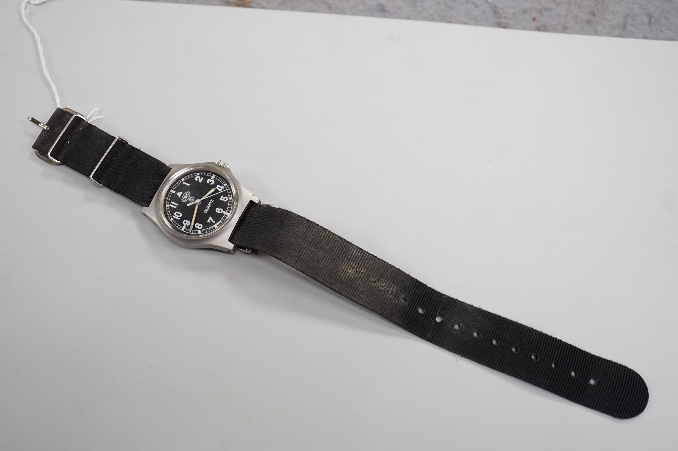 A steel? military CWC pilot's quartz wrist watch, with black Arabic dial, the case back with broad arrow and numbered, 0552/6645-99 over 5415317 over 45825 over 89, on a black fabric strap.